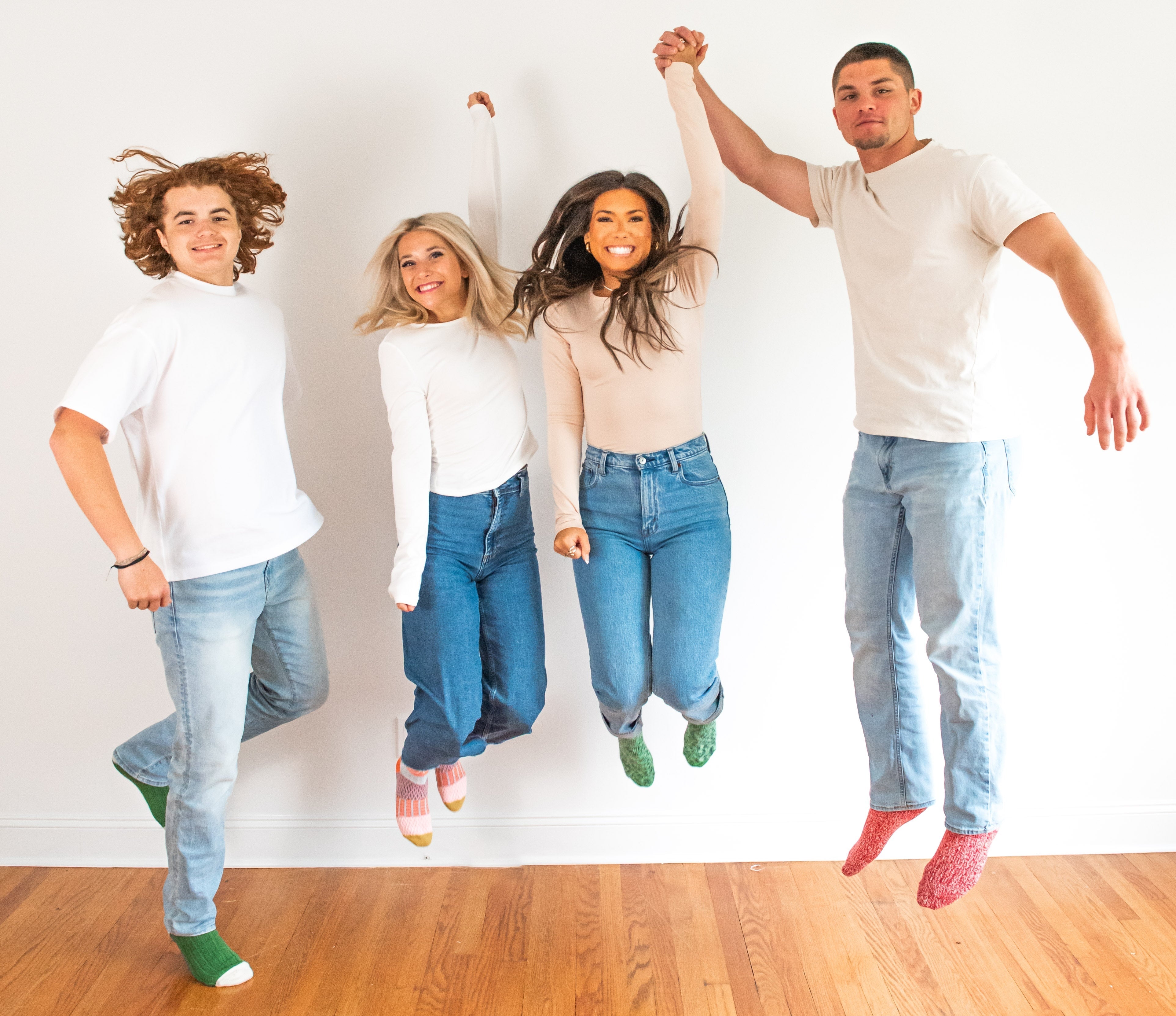 2 girls and 2 boys in plain tops with jeans and colorful socks jumping inside